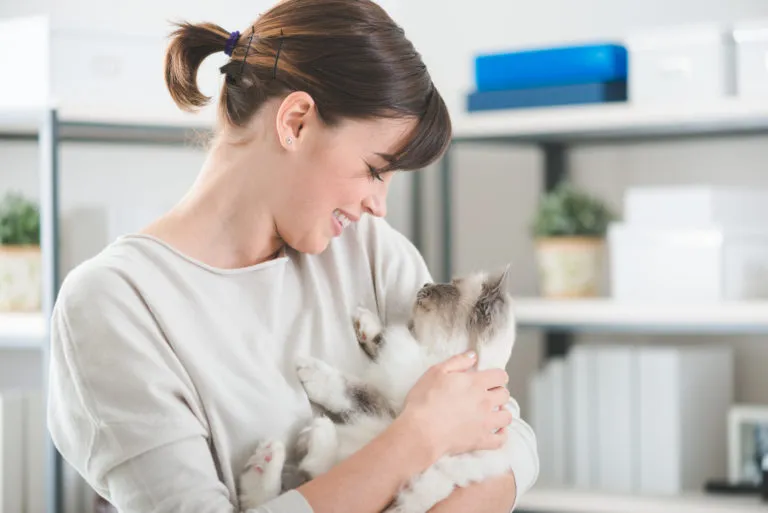 Jeune femme qui tient un chaton blanc et gris dans ses bras