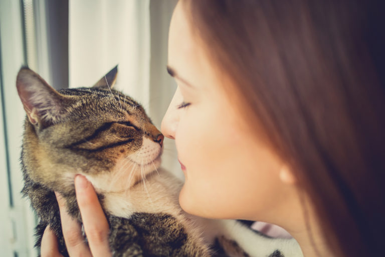 Jeune femme qui porte un chat et met son nez contre le museau du chat