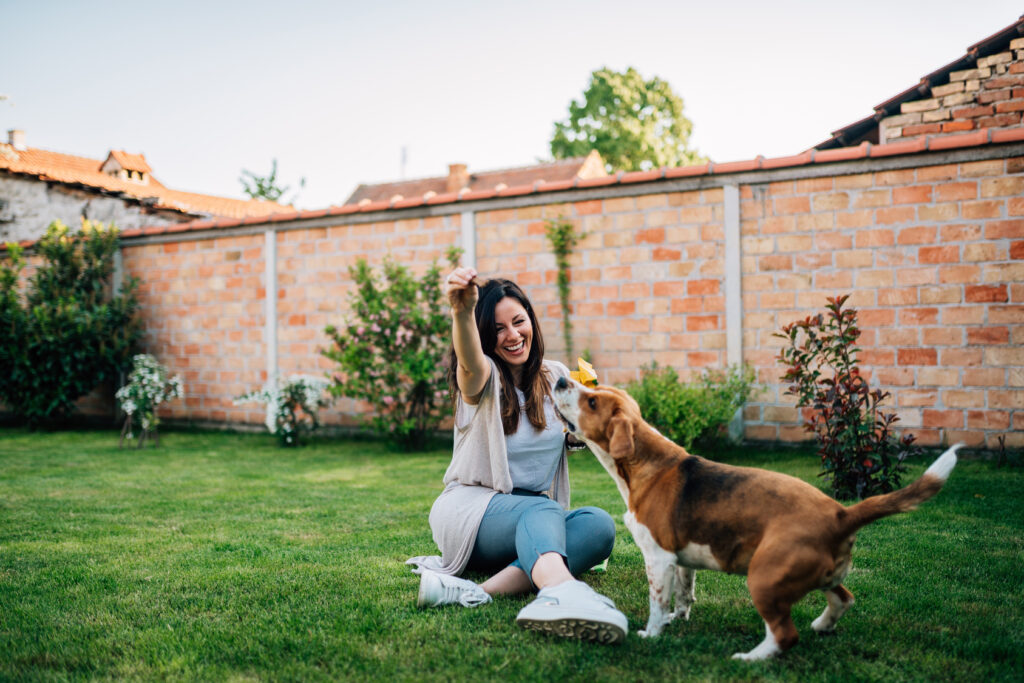 Une jeune femme joue avec son chien heureux dans le jardin.