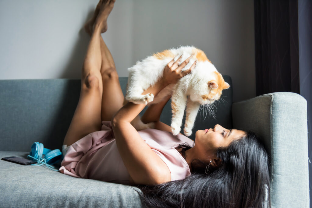 Une jeune femme allongée porte son chat au-dessus d'elle