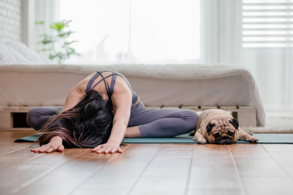 une femme fait du dog yoga avec son carlin