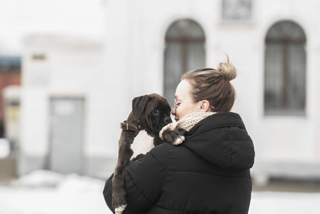 Une jeune femme porte un petit chiot dans ses bras Un jeune chien qui ne veut pas sortir dehors sans sa maîtresse
